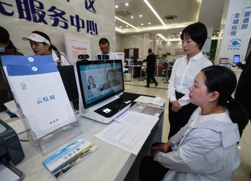2024年5月9日，在嘉兴市秀洲区王江泾镇便民服务中心的“跨域通办·云综窗”窗口，办理开业登记的个体工商户（右一）通过该系统与江苏省苏州市吴江区盛泽镇行政审批局工作人员视频连线，进行身份读取及材料线上审核。新华社记者 徐昱 摄